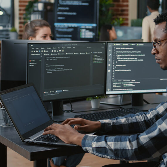 Imported featured image Portrait of tired programer rubbing eyes while typing on laptop sitting at desk with multiple screens parsing code in software agency. Coder losing focus while working on user interface.